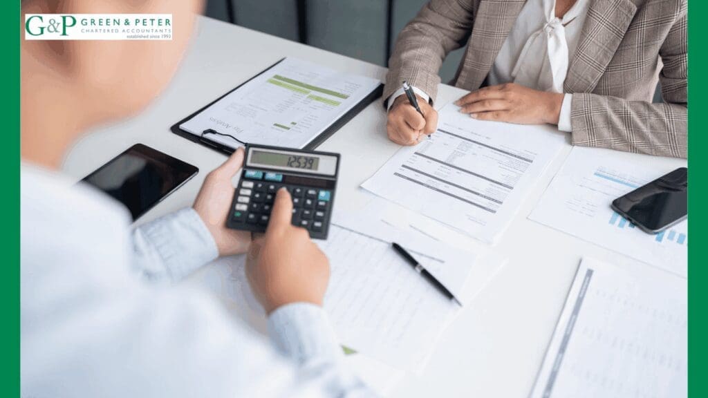 north london auditors at a tab;le working on figures with calculator and paperwork