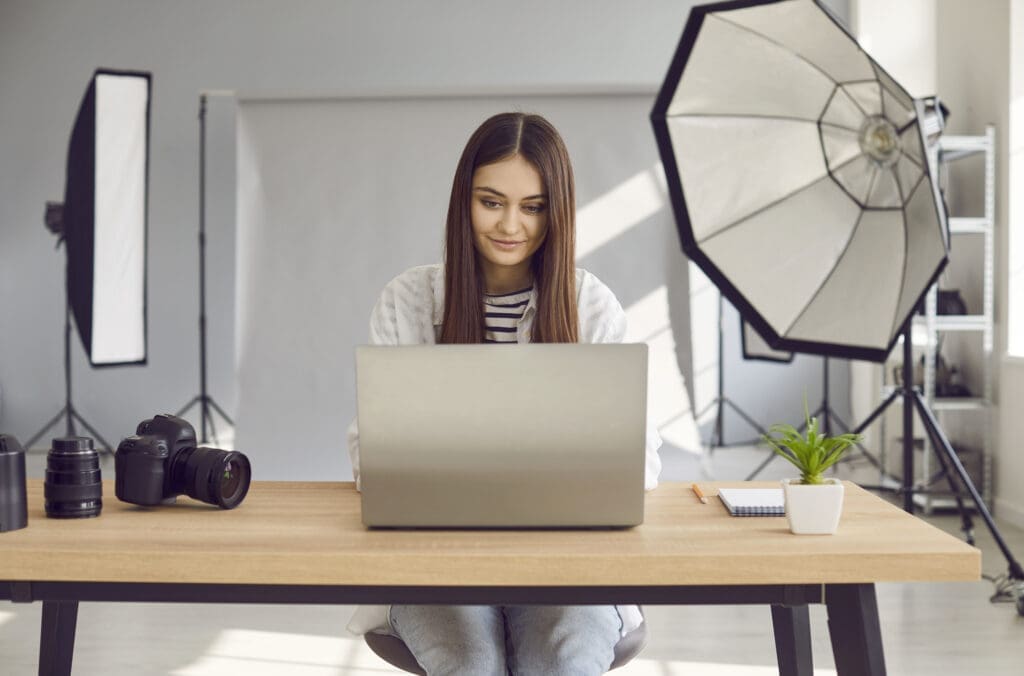 photographer working on laptop in studio with camera equipment, representing photography tax deductions in london.